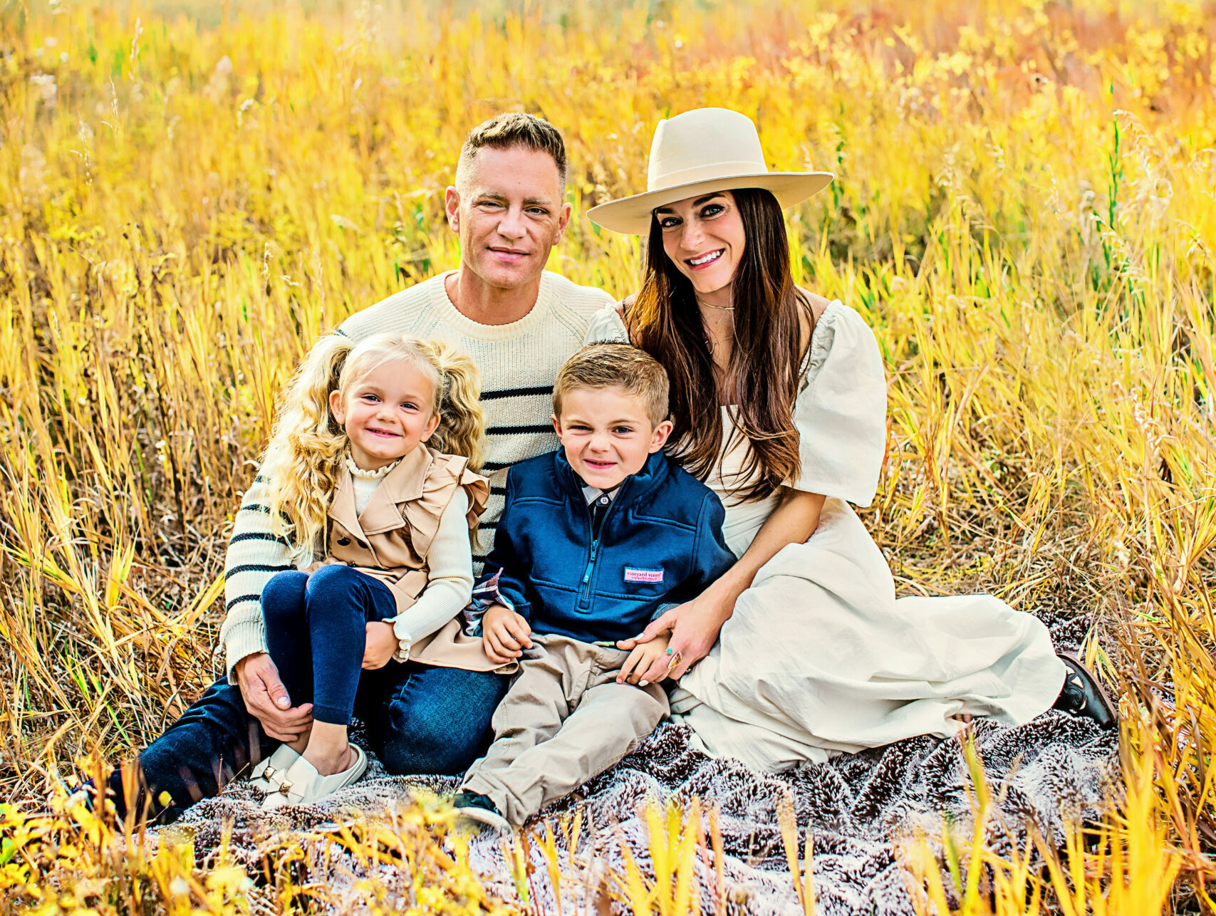 Family sitting in field with forest behind them